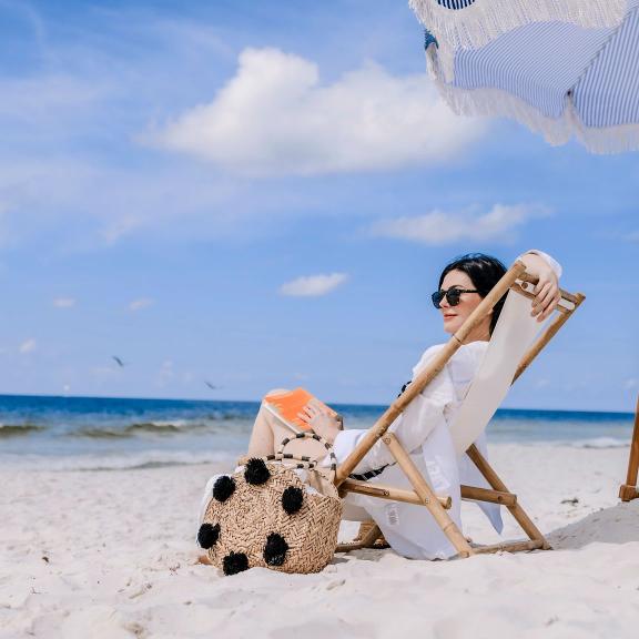 Woman sitting in a beach chair under an umbrella on the beach in Gulf Shores